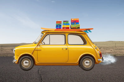 Small car with surfboard and games stacked on the hood.