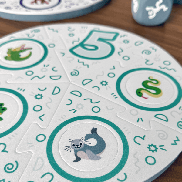 Dance Like a Lemur game from SimplyFun. Featuring a colorful box with playful lemur illustration and foam game puzzle pieces and die with a variety of animal and icon imagery. -SimplyFun