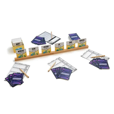 A game set displayed on a white background, featuring six cards in a card holder and four player setups with cards, pencils, and notepads. 